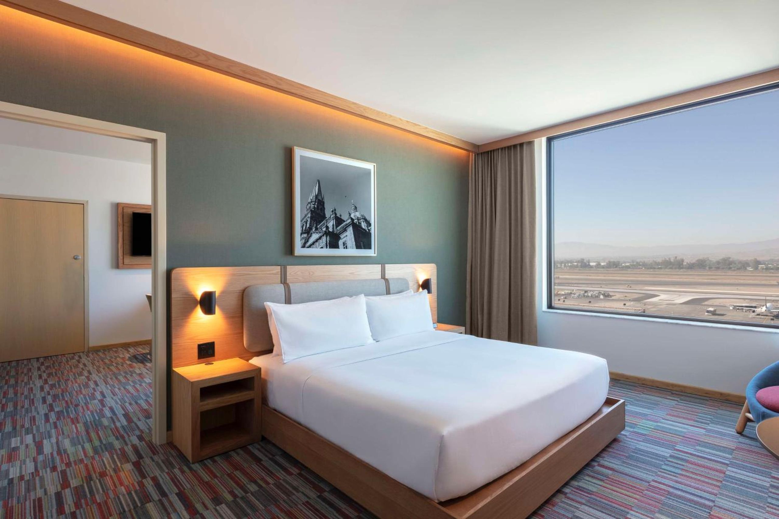 Suite de un dormitorio con cama king y vista al aeropuerto